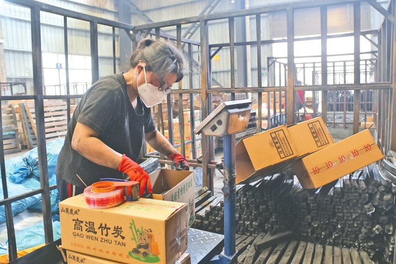 生产车间里,村民在打包竹炭。