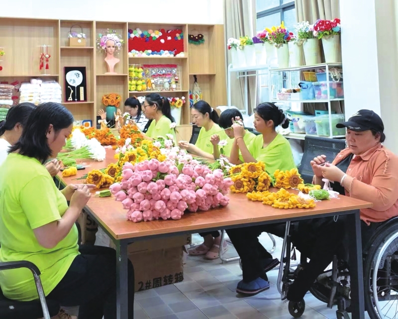 在市残疾人托养服务中心“美丽工坊”,几位残疾人及家属正低头专注制作绒线花。